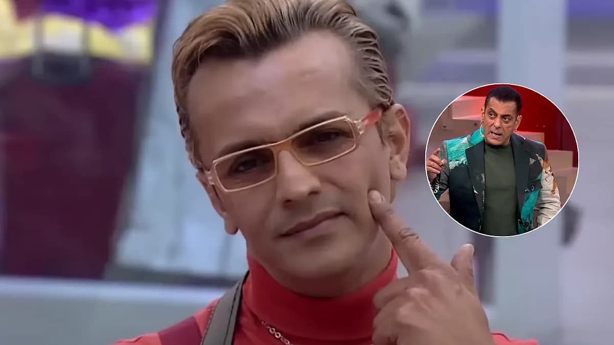 Imam Siddique standing in front of a red curtain, looking directly at the camera.
