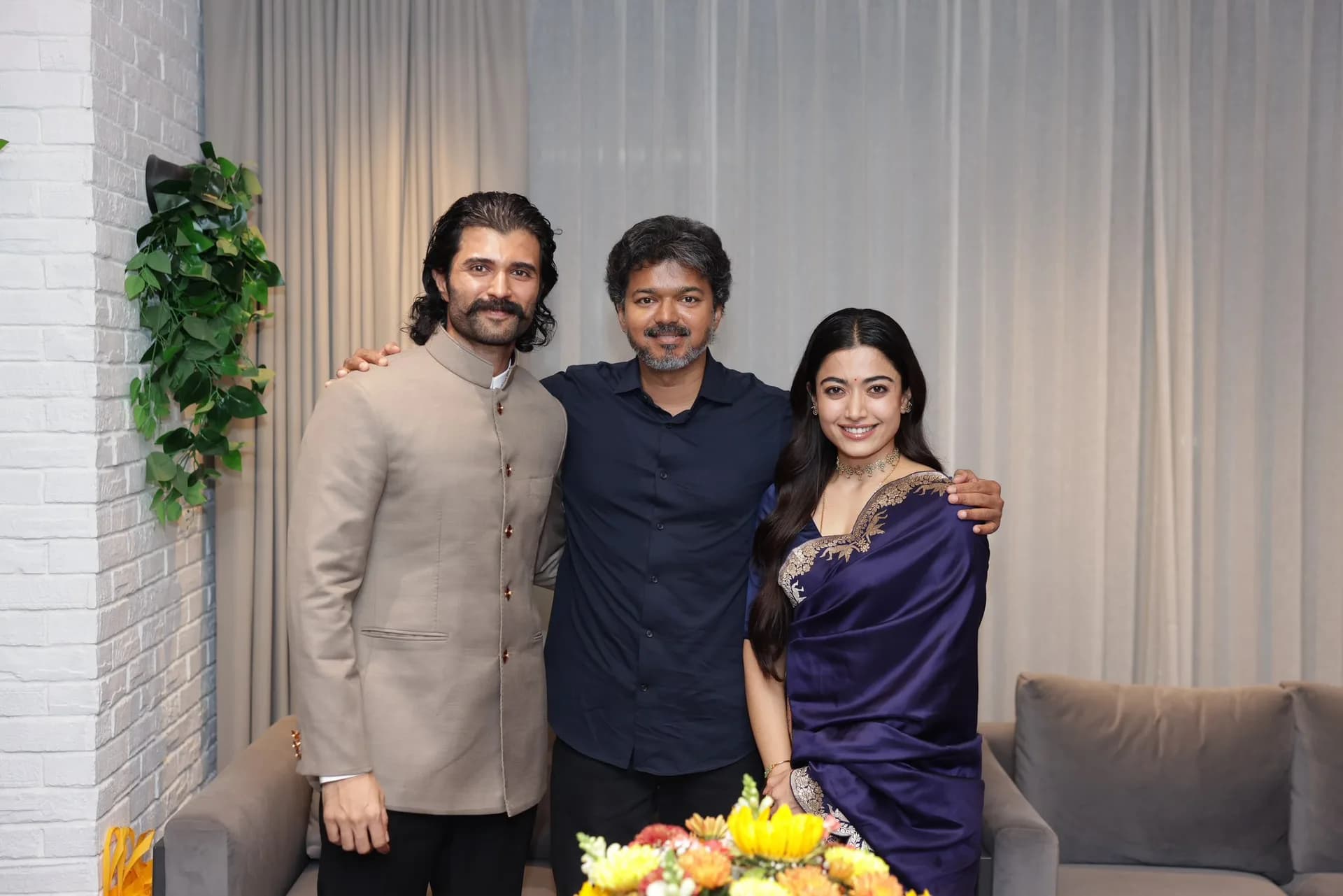 Vijay Deverakonda and Rashmika Mandanna standing beside Tamil Nadu Chief Minister Thalapathy Vijay, smiling at the camera.