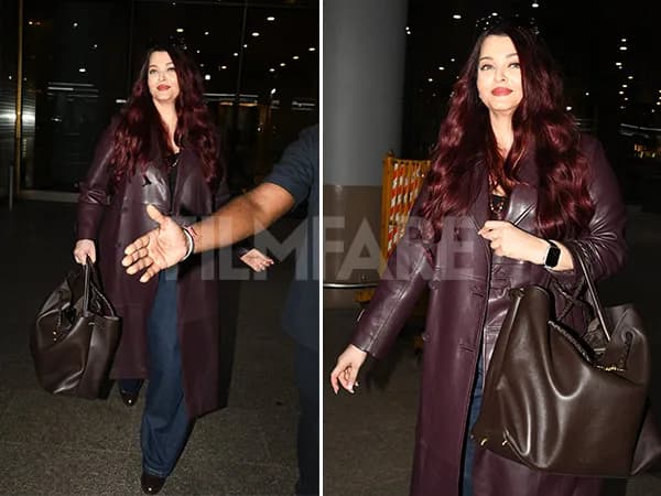 Aishwarya Rai Bachchan wearing a plum leather trench coat, black tee and flared denim at Mumbai airport, holding a Bottega Veneta bag.