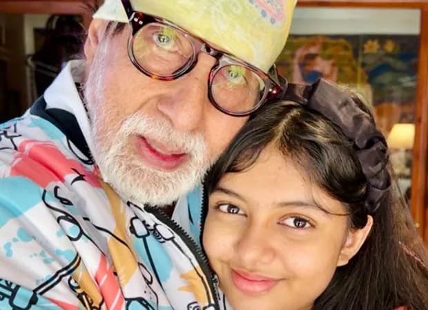 Amitabh Bachchan in a tracksuit and beanie, hugging granddaughter Aaradhya Bachchan. A warm, candid moment.