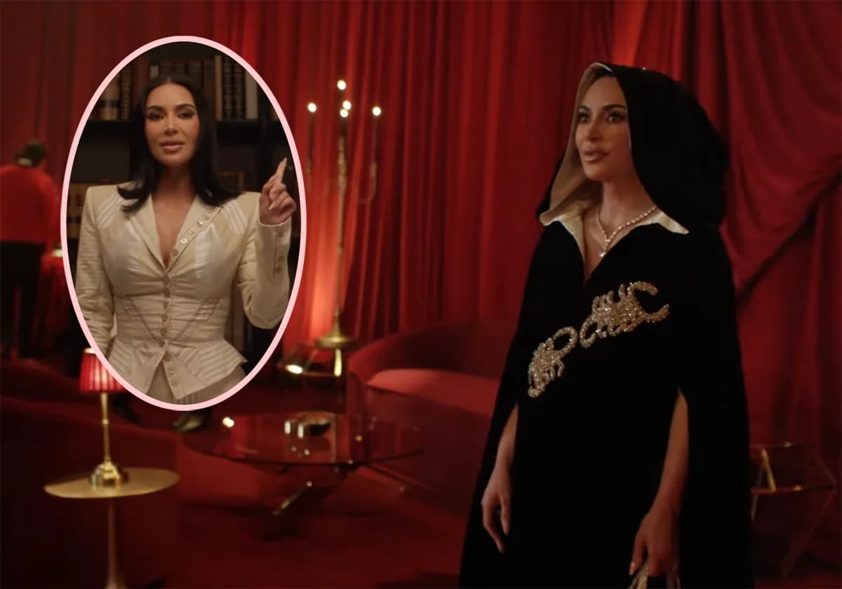 Kim Kardashian in a red robe, standing in a candlelit red room, looking solemn.