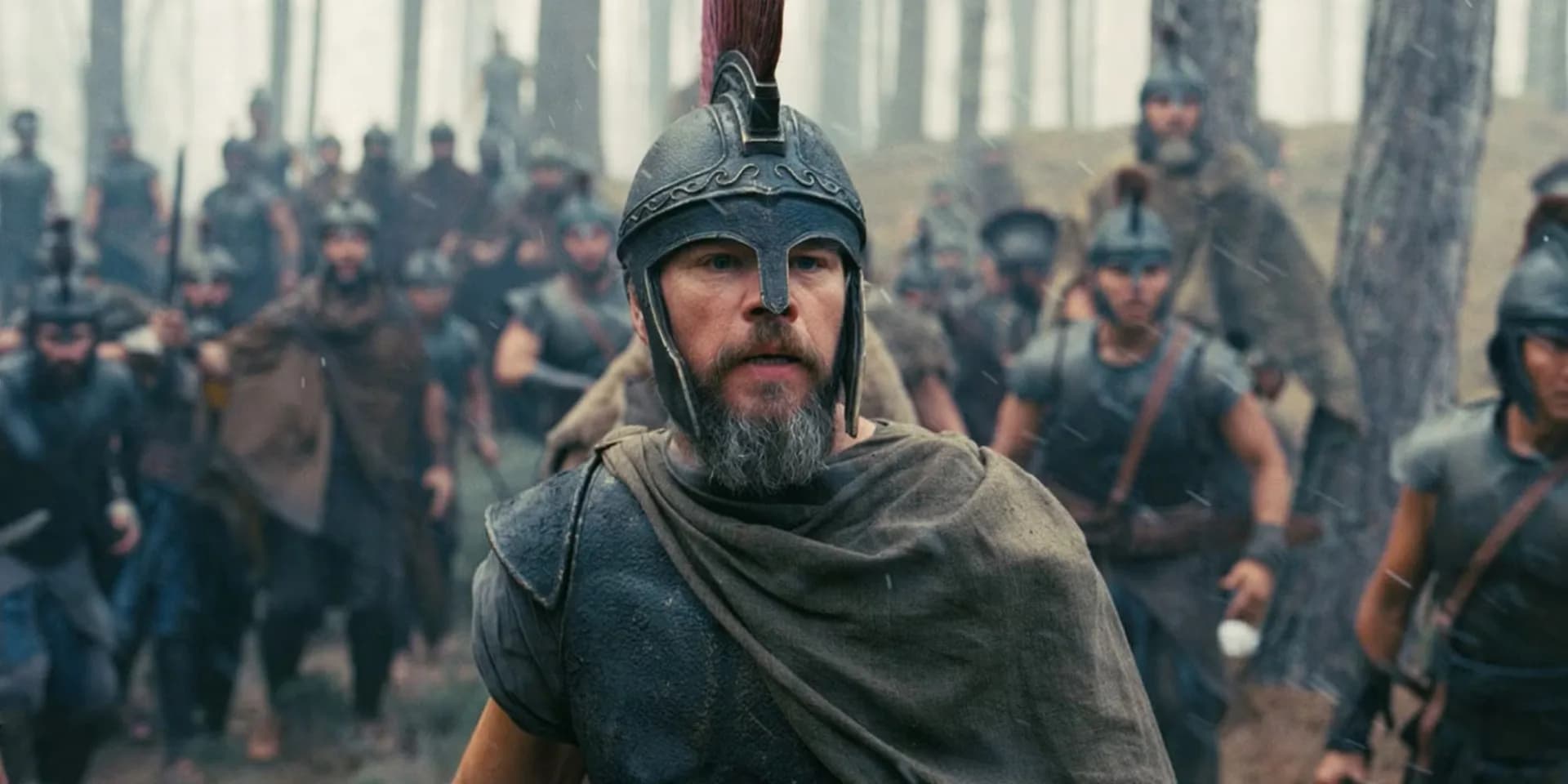 Matt Damon in a weathered, battle-worn look, standing on a cliff overlooking the sea, his face etched with exhaustion and resolve.