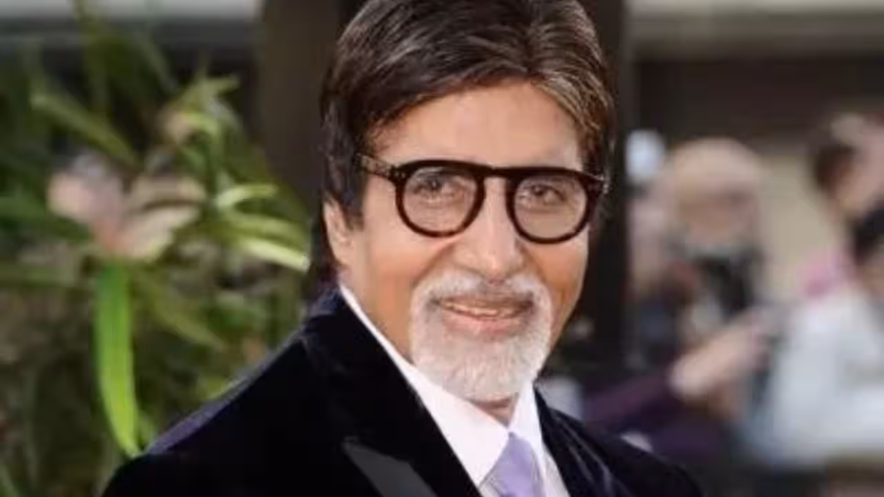 Amitabh Bachchan seated at the centre of the KBC stage, looking at the camera with a calm expression.