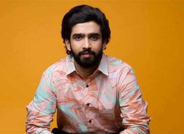 Composer Amaal Mallik at a public event, speaking into a microphone.