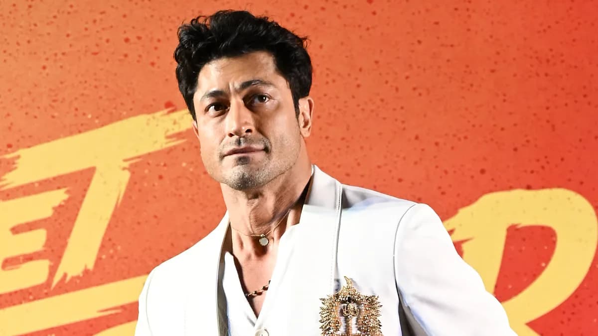 Vidyut Jammwal smiling at a press event, holding a microphone.