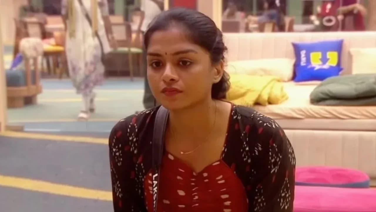 Lakshmi Priya standing at the exit door of the Bigg Boss Tamil house, looking back at the camera.