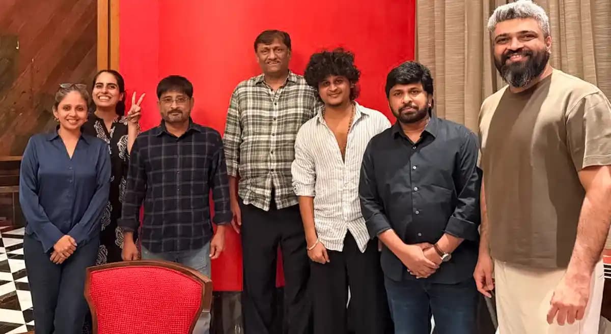 A group of filmmakers celebrating at a Netflix-hosted event, holding banners with 'Irumudi' and 'Modha Rathri'.