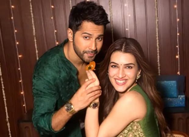 Varun Dhawan and Kriti Sanon in a warm Diwali setting, laughing over mithai, with Fossil watches subtly visible on their wrists.