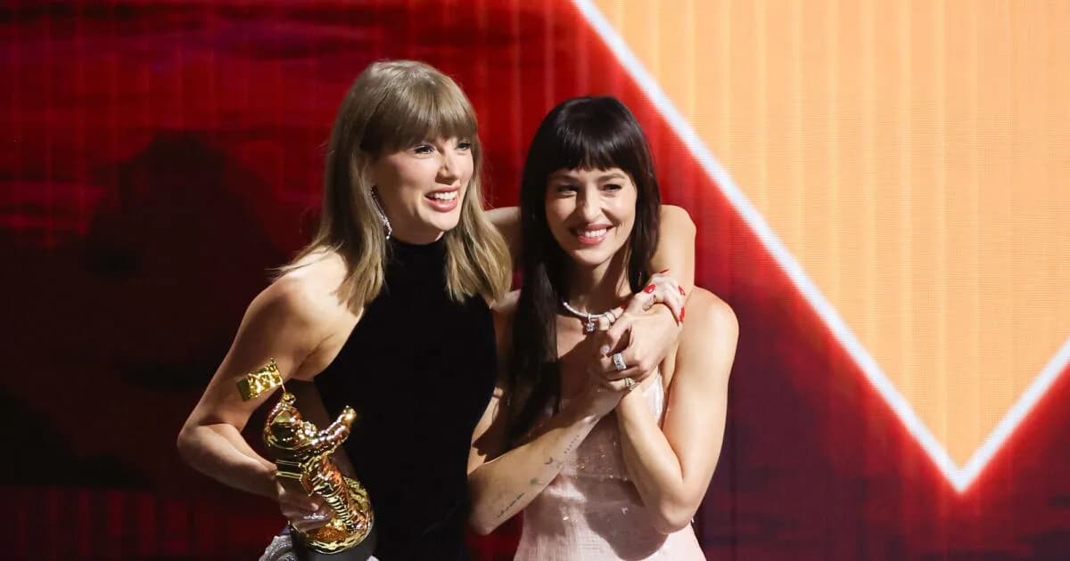 Taylor Swift on stage at the MTV Video Music Awards holding a Moon Person trophy while a large screen shows her new ‘Patient Zero’ video.