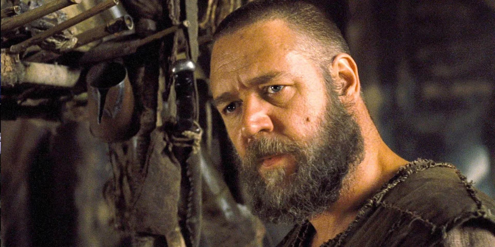 A still from Noah (2014) showing Russell Crowe as the titular character standing on a cliff overlooking a stormy sky.