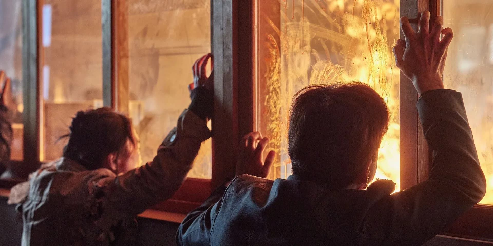 A teenage girl in a school uniform, face streaked with dirt and blood, staring into the camera from behind a broken classroom window. Outside, shadows move in the hallway.