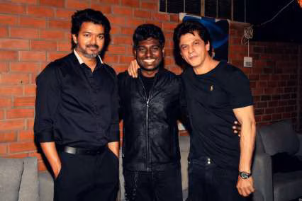 Atlee standing beside Vijay and Shah Rukh Khan at a promotional event for Jawan