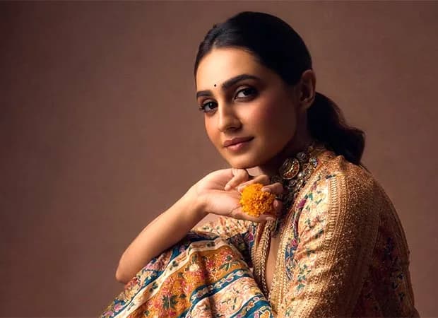Vedika Pinto in a vibrant multicoloured lehenga with a mustard-yellow dupatta, standing in front of a decorated garba ground.