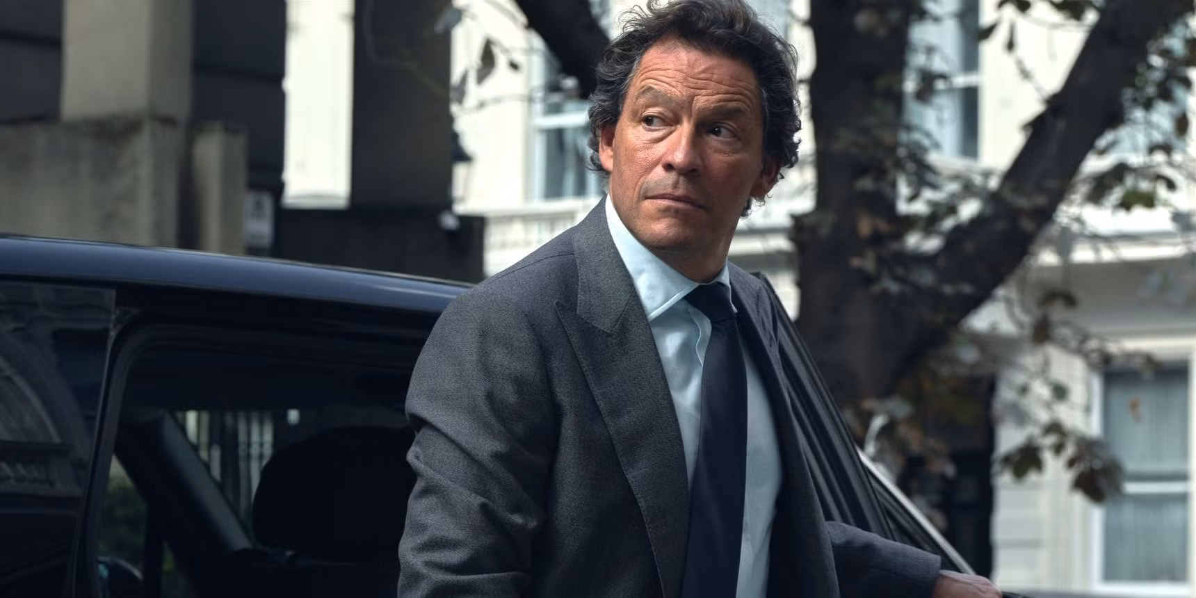 Dominic West and Sienna Miller in a tense courtroom scene, shadows falling across their faces.