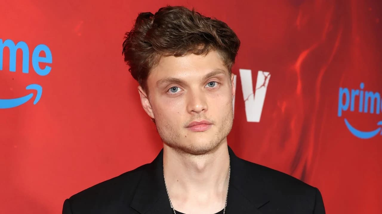 Asa Germann attends a red carpet event in a dark suit, smiling for photographers.