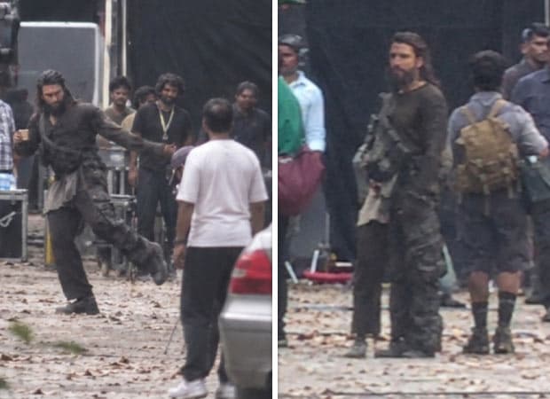 Ranveer Singh with a beard and long hair walking on the sets of Pralay, carrying a child on his back.
