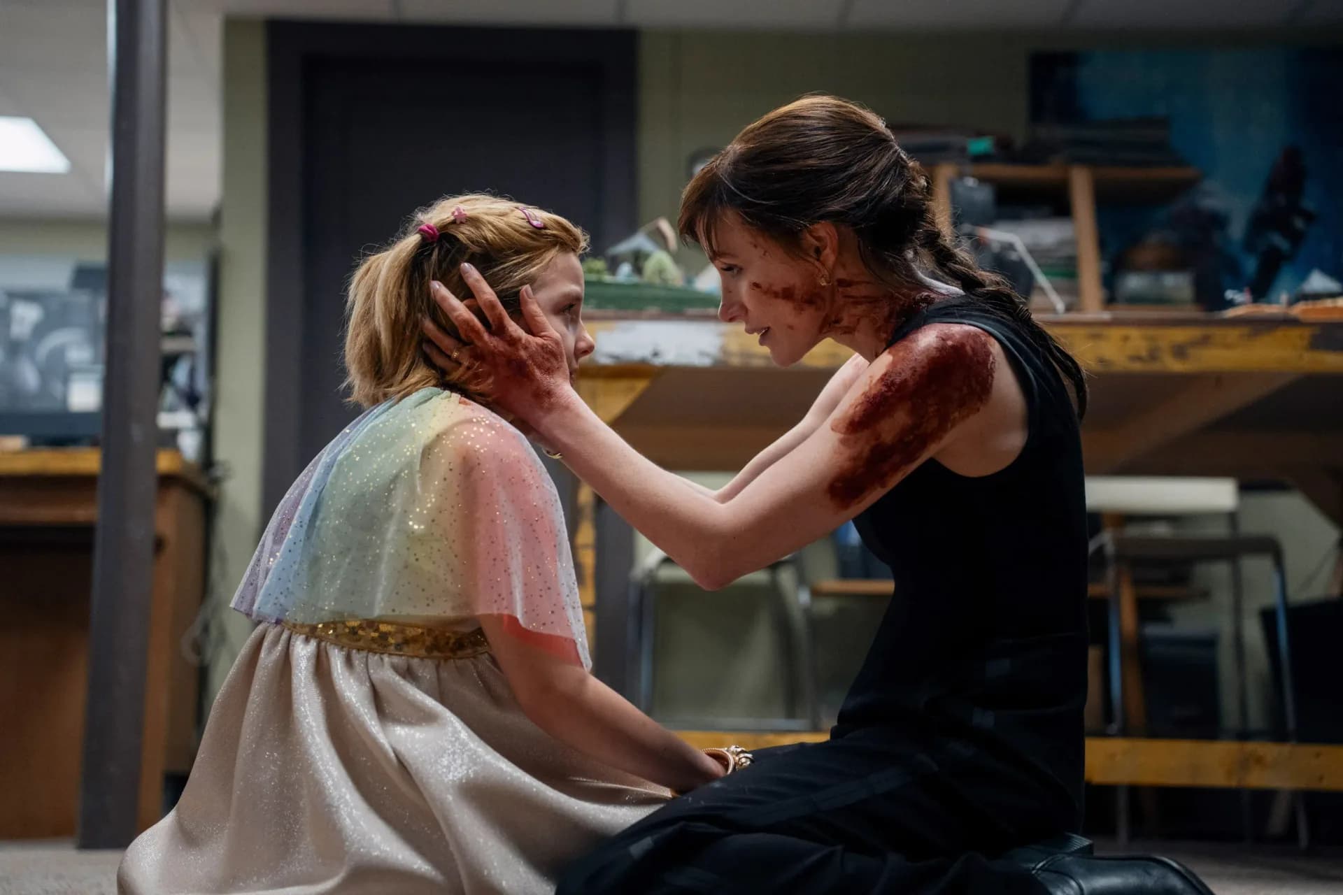 A tense scene from the film 'Other Mommy' showing a child looking frightened while a shadowy figure looms behind her mother.