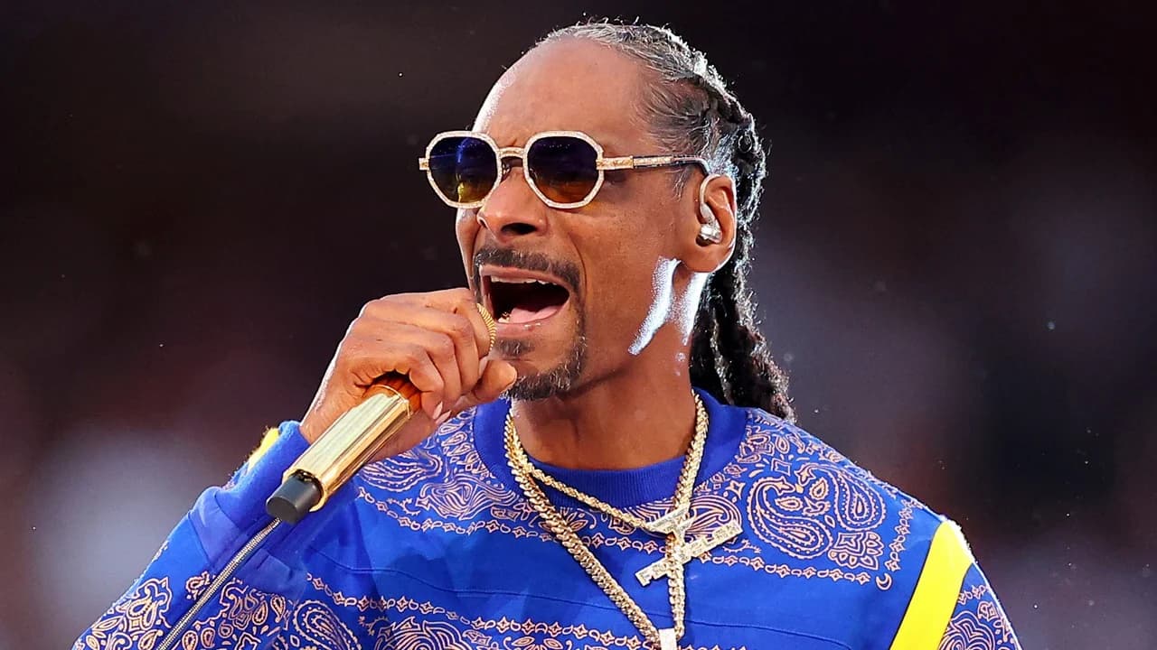 Snoop Dogg smiling in a suit at a public event