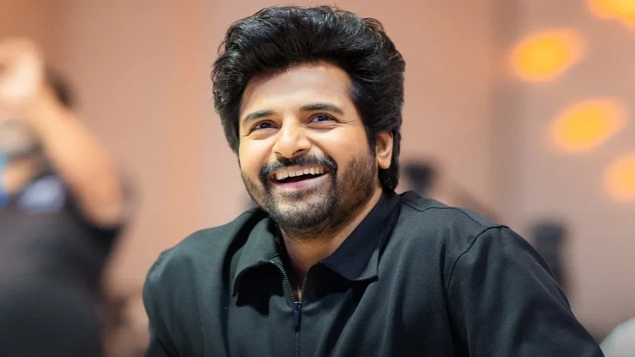 Sivakarthikeyan at a fan meet, holding a microphone, smiling confidently