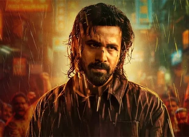 Emraan Hashmi in a black vest and rexine jacket, standing in a dimly lit Bangkok alley, looking over his shoulder.