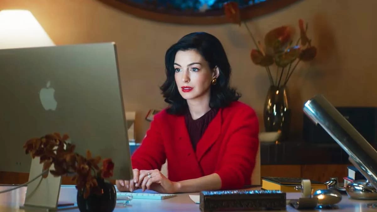 Anne Hathaway in a tense scene from Verity, standing in a dimly lit study with a book open on a desk.