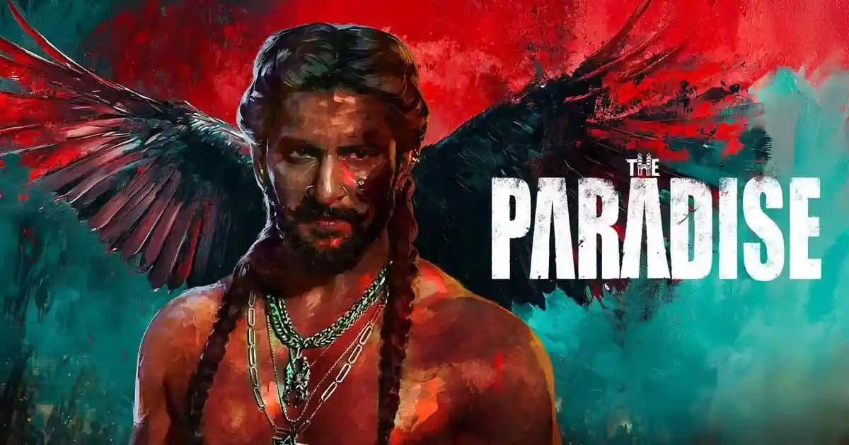 Nani standing at a press event holding a The Paradise poster, smiling while addressing media.