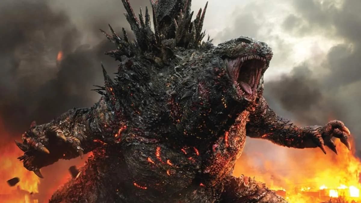 A still from Godzilla Minus Zero showing the monster towering over a ruined city, smoke rising in the background.
