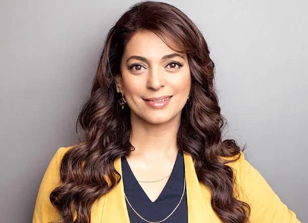 Juhi Chawla smiling at a public event, dressed in formal attire
