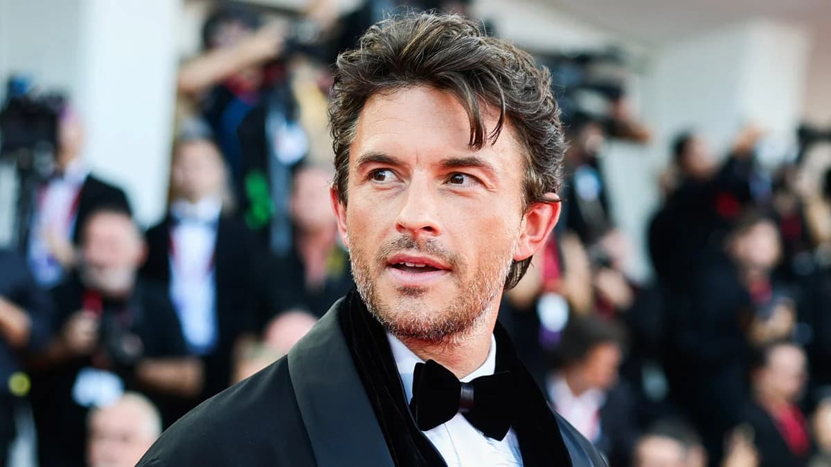 Jonathan Bailey walking through an airport in Venice wearing a dark outfit, photographed leaving the city after the film festival.