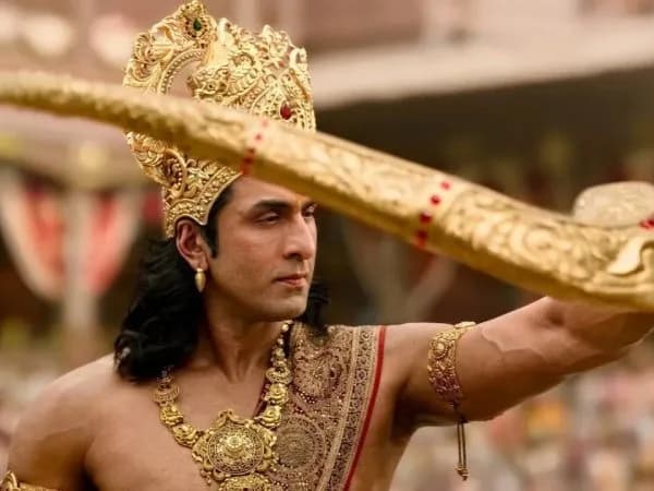 Ranbir Kapoor as Lord Rama in a dramatic pose, standing in front of a temple gate under a stormy sky