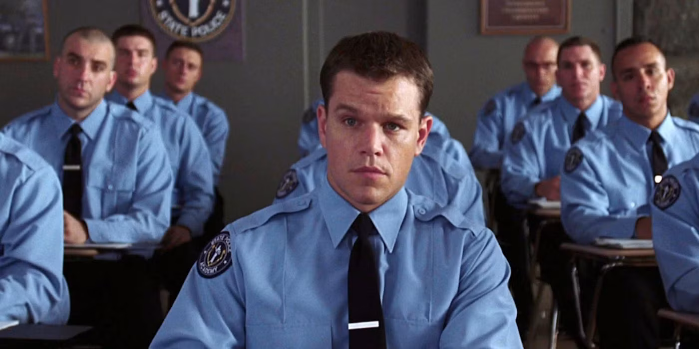 Matt Damon in a suit, looking tense, standing in a dimly lit police station.