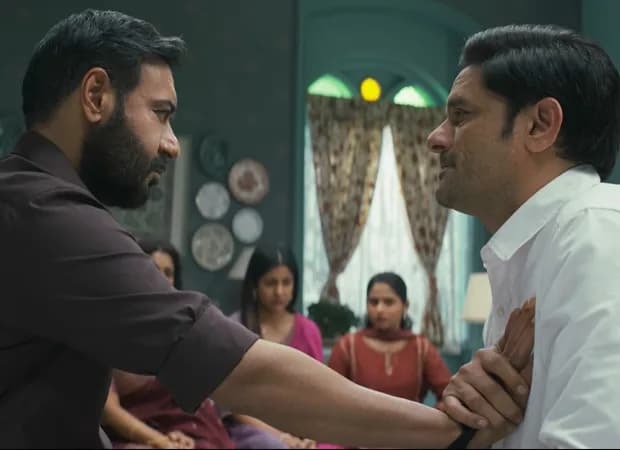Ajay Devgn in a tense scene from Drishyam: The Conclusion, eyes locked on camera, face half-shadowed.