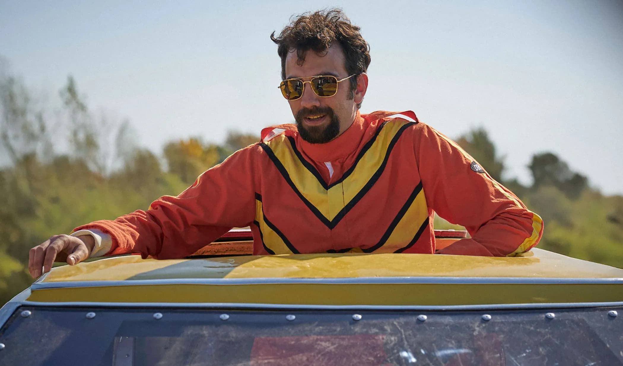 Jay Baruchel in period costume as stunt driver Ken Carter standing beside a rocket-powered car
