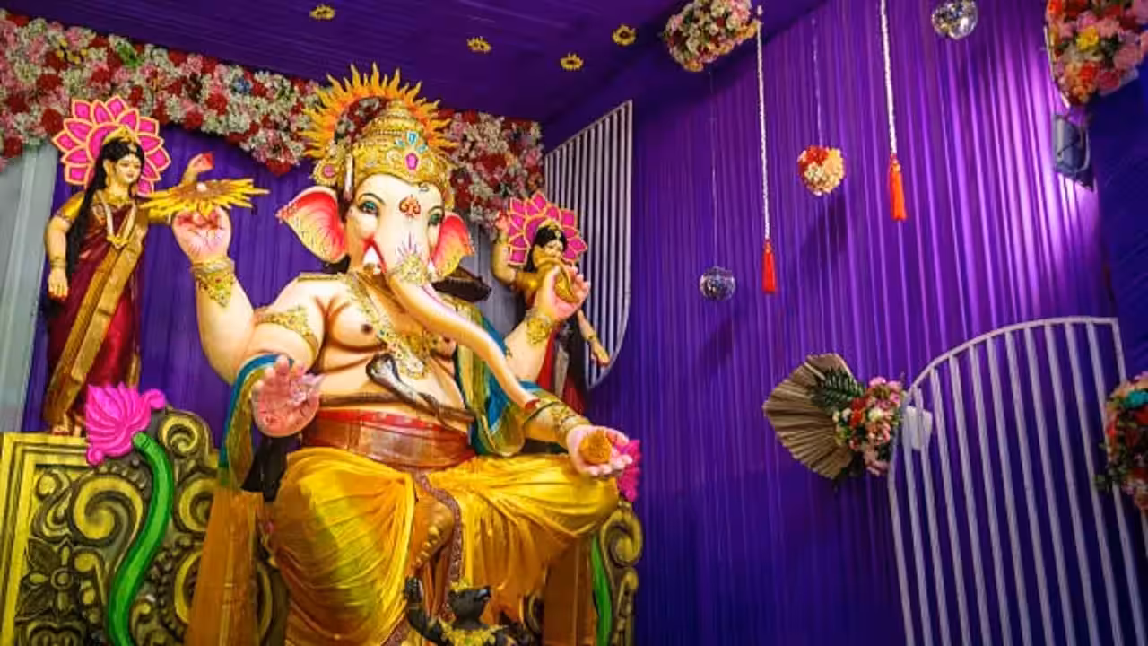 A home Ganpati mandap decorated with marigold garlands, warm fairy lights and a draped fabric backdrop ahead of Ganesh Chaturthi.