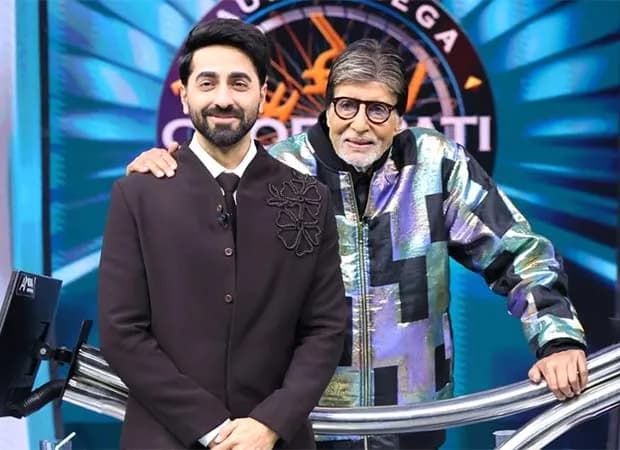 Amitabh Bachchan seated at the KBC desk, eyes closed, listening intently as Ayushmann Khurrana sings 'Kabhi Kabhie Mere Dil Mein'
