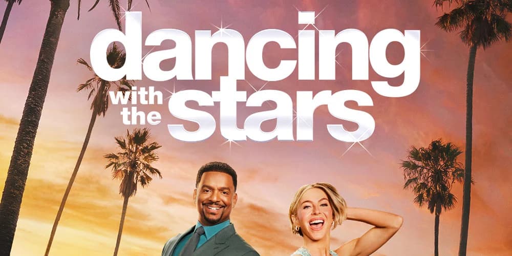 A Dancing With the Stars ballroom stage with judges seated at their desk during a live broadcast.
