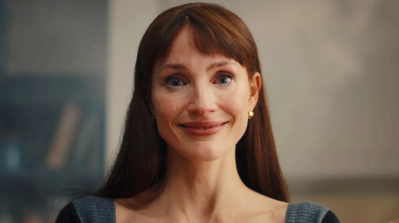 Jessica Chastain staring into the camera, eyes wide, in a dimly lit room. A shadowy figure looms behind her.