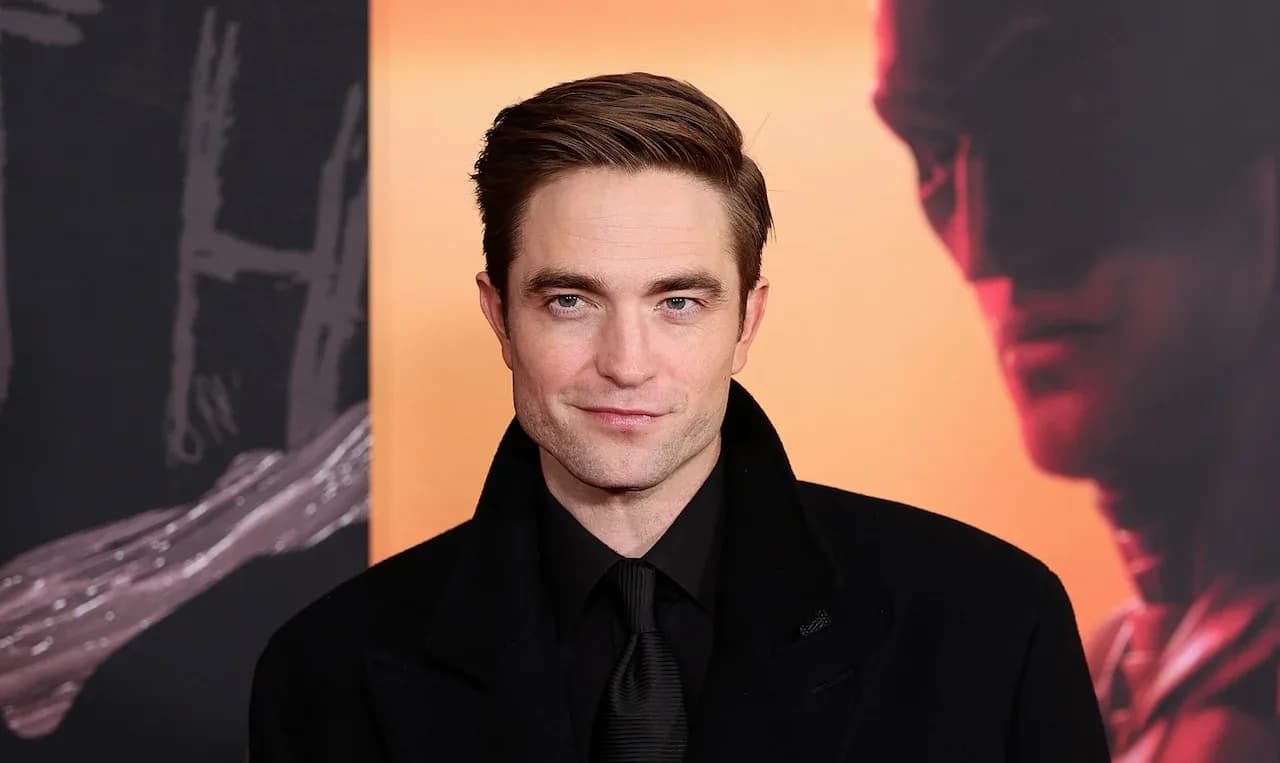 Robert Pattinson as Batman in a dark, rain-soaked Gotham street, looking up at the sky
