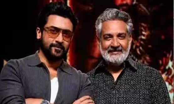 SS Rajamouli speaking on stage at a promotional event alongside actor Suriya