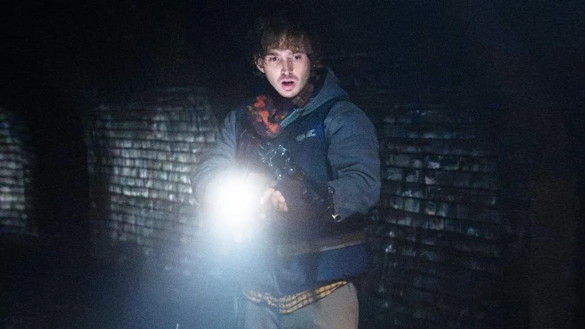 A still from Resident Evil featuring Austin Abrams in a tense scene against a zombie.