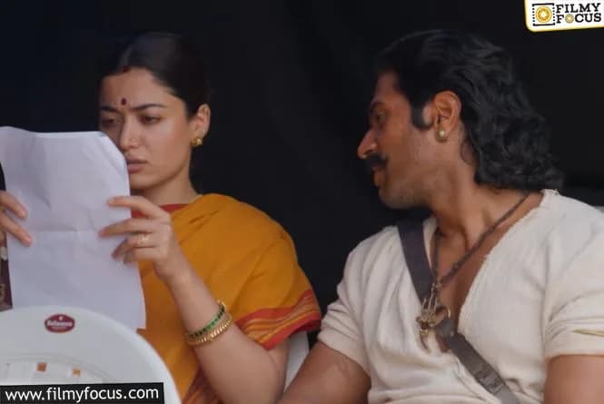 Vijay Devarakonda and Rashmika Mandanna standing beside a historic Indian railway line, discussing colonial transport of agricultural goods.