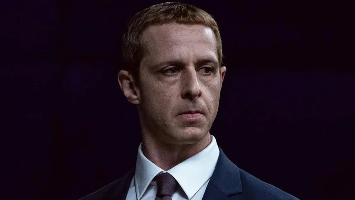A dimly lit theater screen showing a blurred image of Jeremy Strong in a suit, with the words 'The Social Reckoning' fading out. A red 'X' overlays the frame.