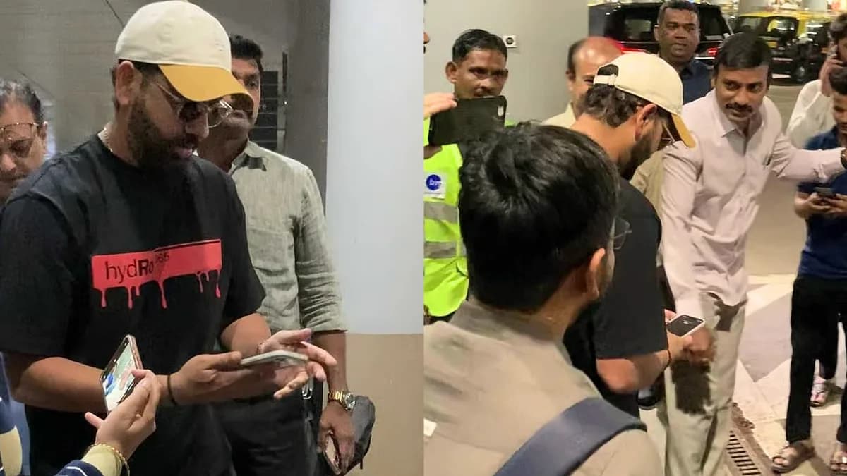 Rohit Sharma bending down to pick up his phone after it slipped from his hand at Mumbai Airport
