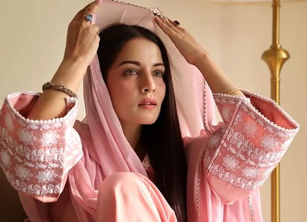 Celina Jaitly holding a handwritten note, looking solemn, with a soft background.