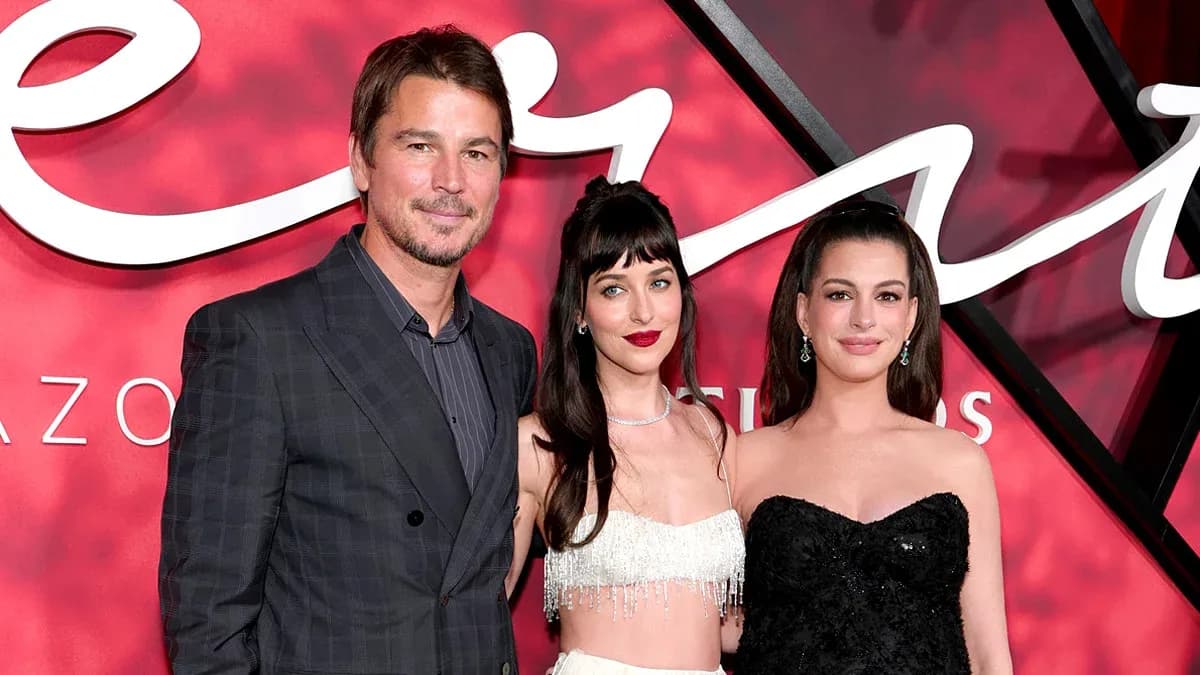Anne Hathaway in a black embellished gown showing her pregnancy on the red carpet at the Verity premiere in New York, standing near Dakota Johnson.
