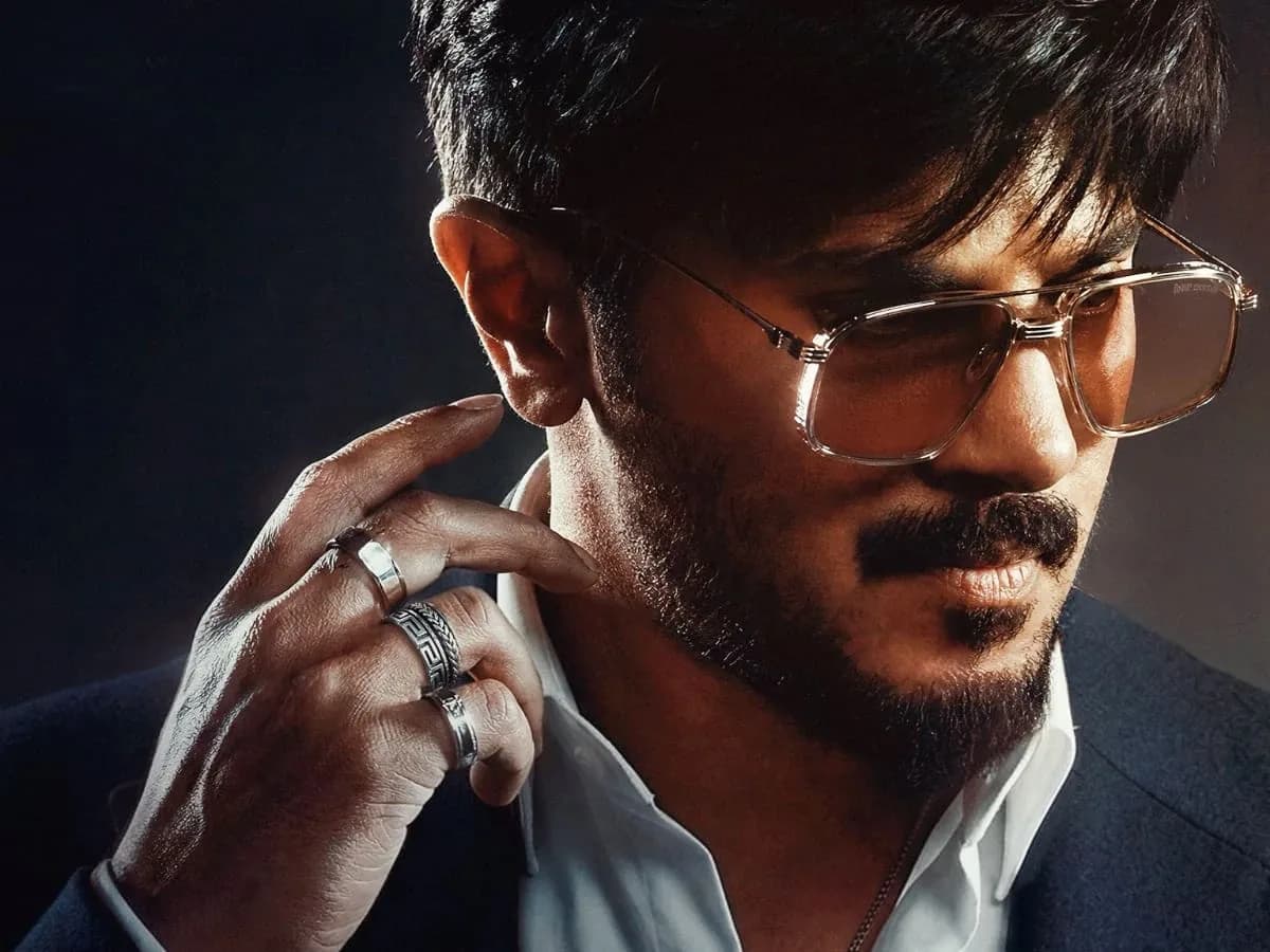 Dulquer Salmaan in I'm Game, standing in a dimly lit room with a glowing hand