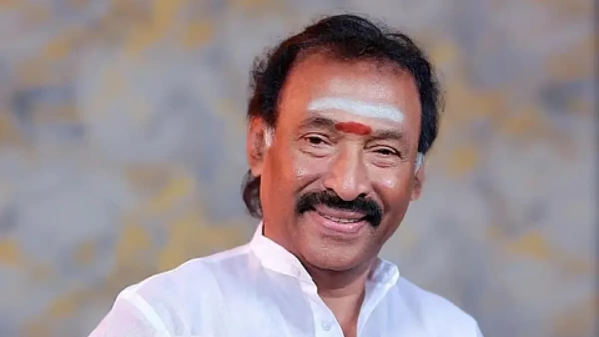 Portrait of Tamil music director Deva in white kurta and sandals, smiling during a performance.