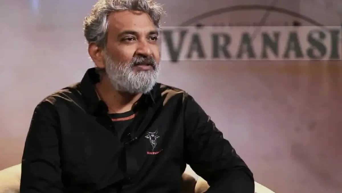 SS Rajamouli standing in front of a temple, holding a script