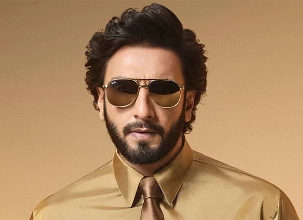 Ranveer Singh wearing Ray-Ban glasses, standing in front of a city skyline