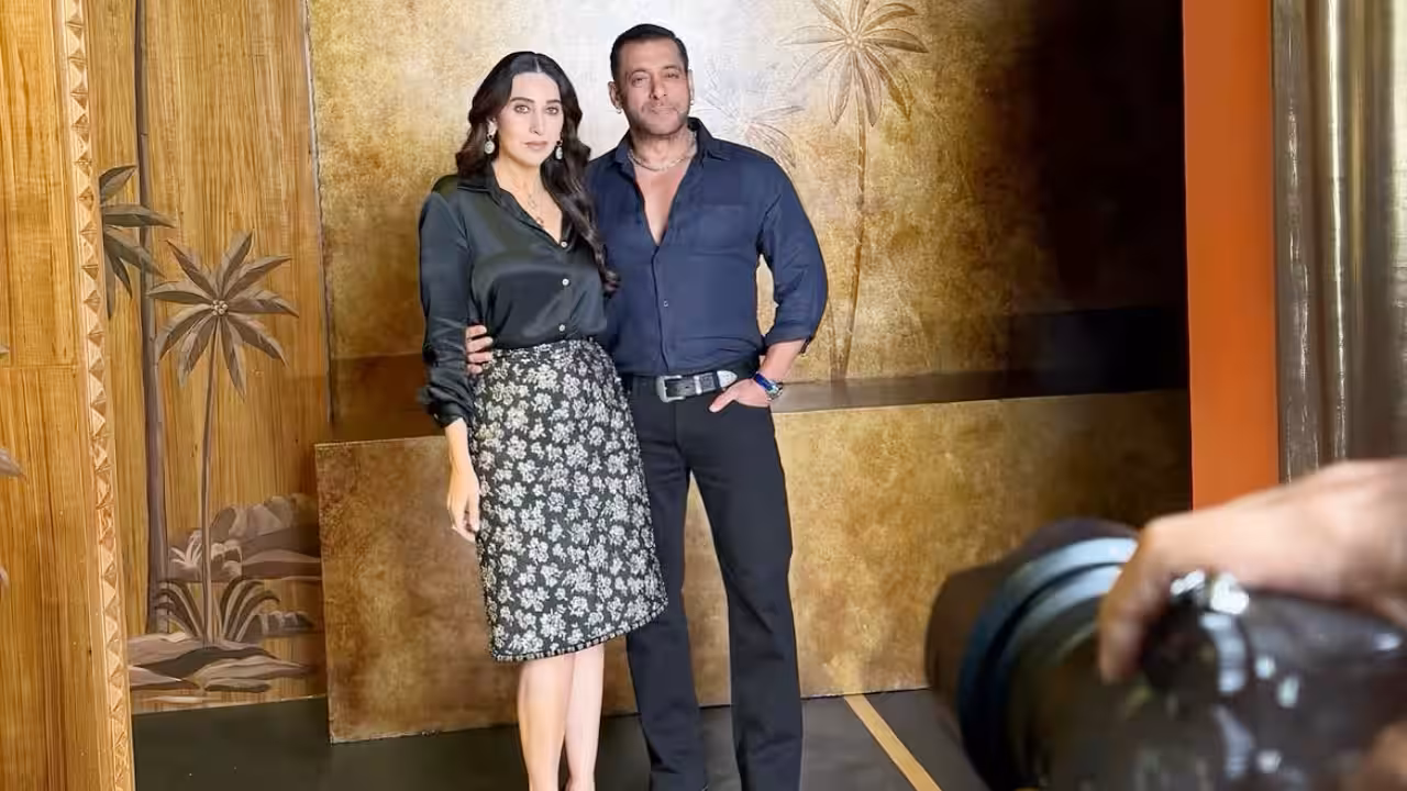 Karisma Kapoor in a black Sabyasachi outfit with layered jewellery, seated on a couch with Salman Khan.